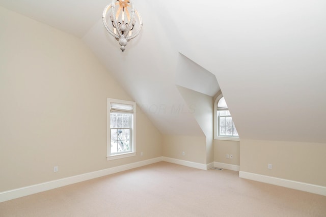 additional living space featuring light carpet, vaulted ceiling, and a notable chandelier