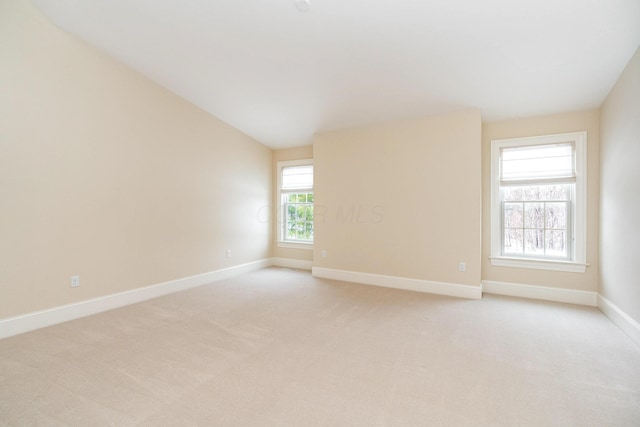 spare room with light colored carpet and vaulted ceiling