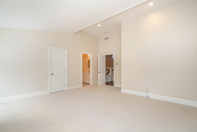 unfurnished bedroom with high vaulted ceiling, carpet, and ensuite bathroom