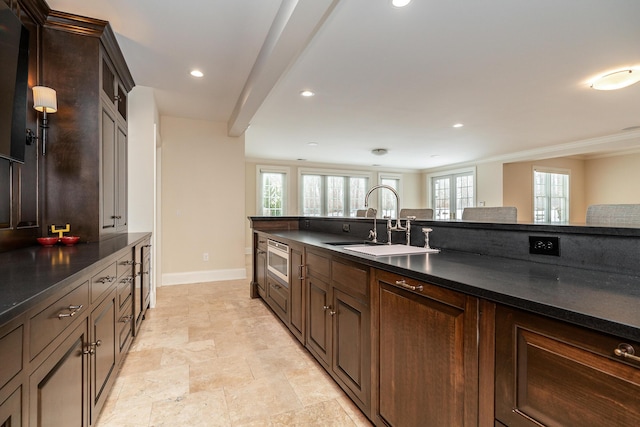 kitchen with sink, ornamental molding, stainless steel microwave, and dark brown cabinetry