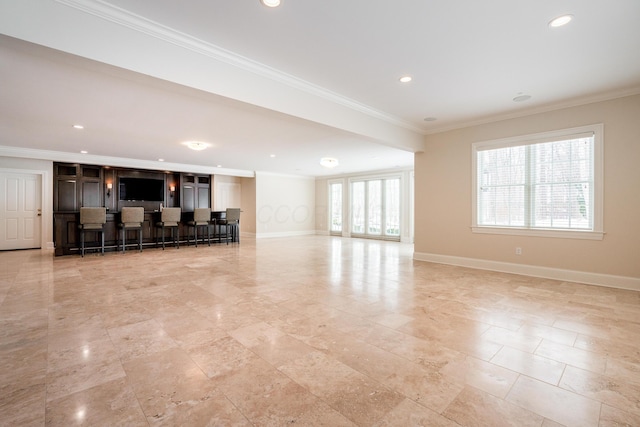 unfurnished living room featuring bar area and crown molding