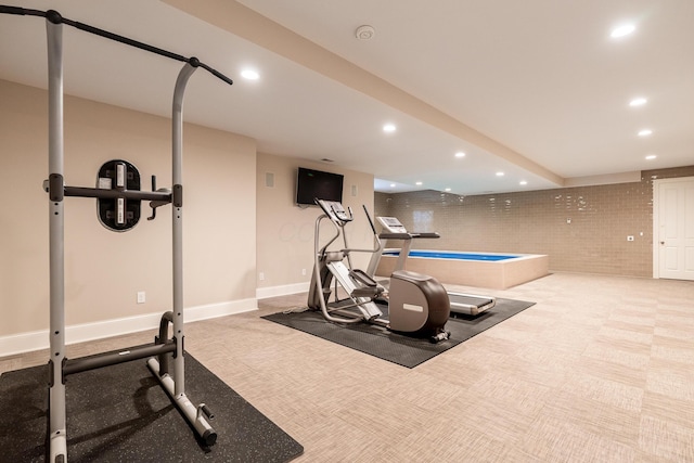 workout room with brick wall and light carpet