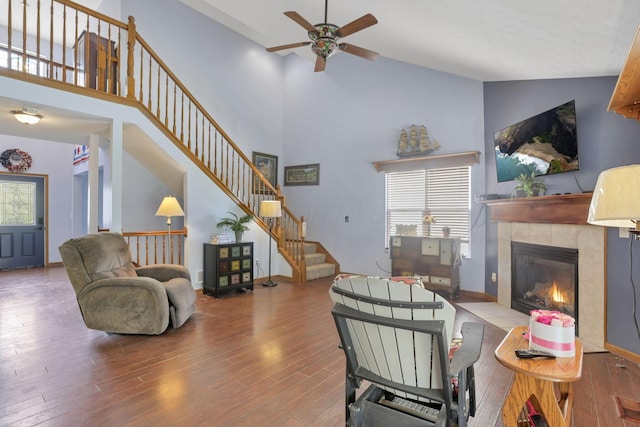 living room with a tile fireplace, ceiling fan, high vaulted ceiling, and wood-type flooring