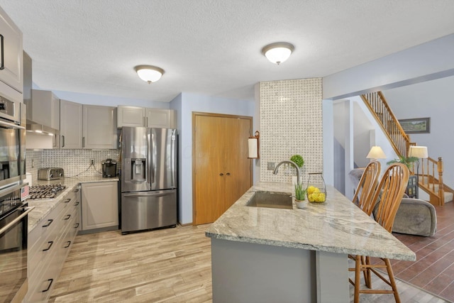 kitchen featuring stainless steel fridge with ice dispenser, light wood-type flooring, a breakfast bar area, and sink