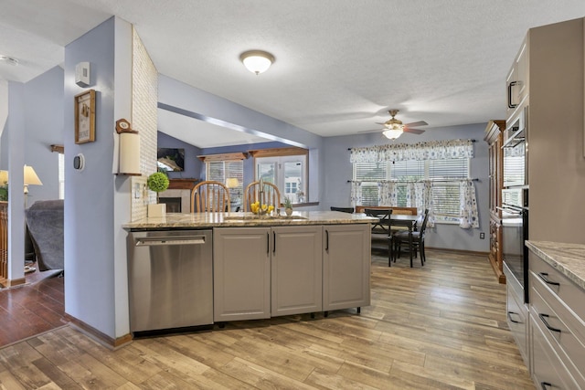 kitchen with light wood-type flooring, stainless steel dishwasher, ceiling fan, and sink