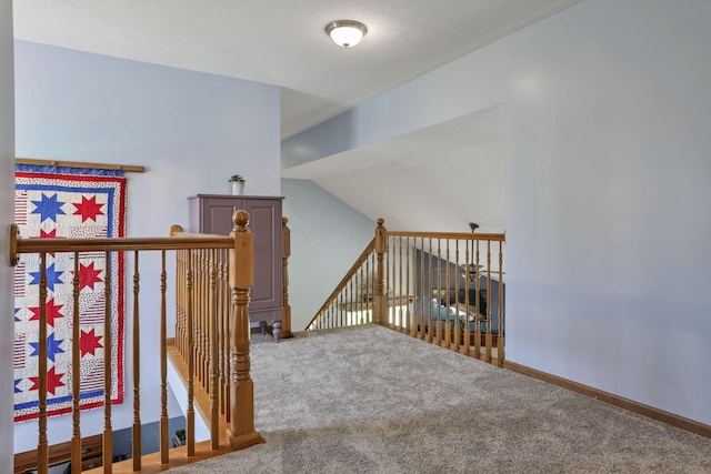 hallway with carpet flooring and vaulted ceiling