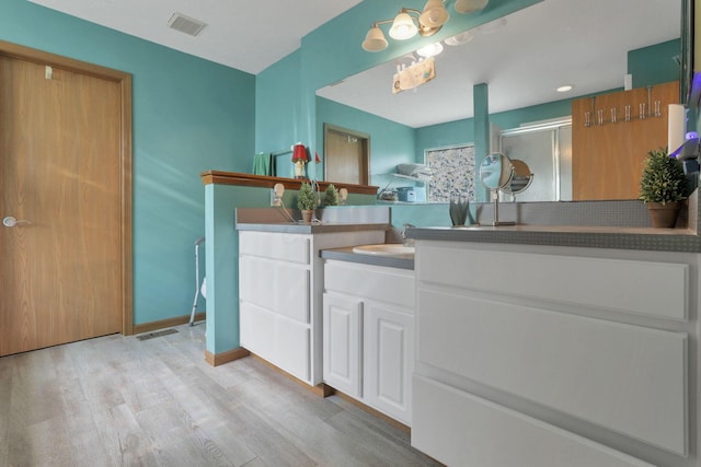 bathroom featuring hardwood / wood-style flooring, vanity, and a shower with door