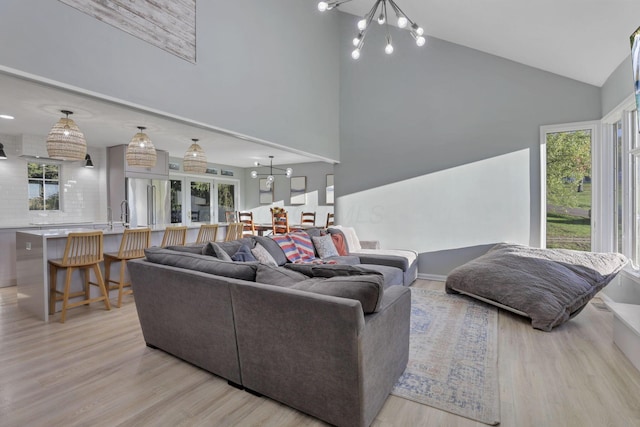 living room featuring high vaulted ceiling, a notable chandelier, and light wood-type flooring