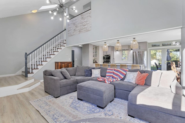 living room featuring french doors, a towering ceiling, and light hardwood / wood-style floors