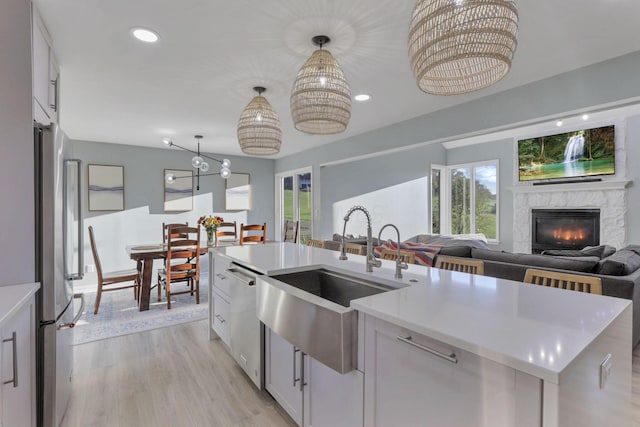 kitchen featuring sink, appliances with stainless steel finishes, white cabinetry, a center island with sink, and decorative light fixtures