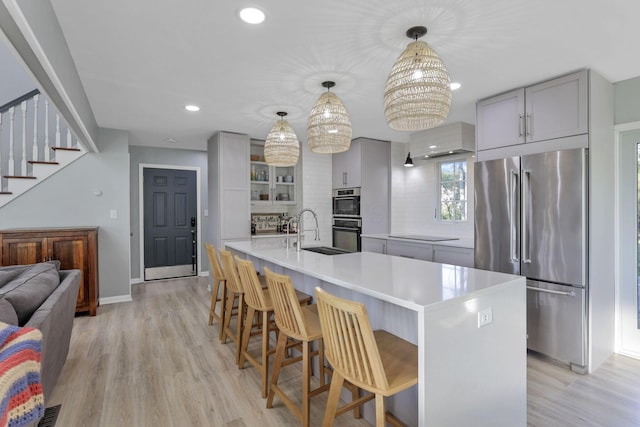 kitchen featuring a spacious island, sink, gray cabinets, pendant lighting, and stainless steel appliances