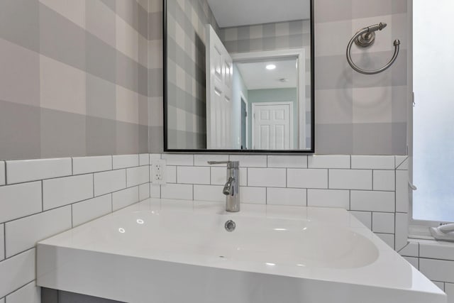 bathroom featuring tasteful backsplash, sink, and tile walls