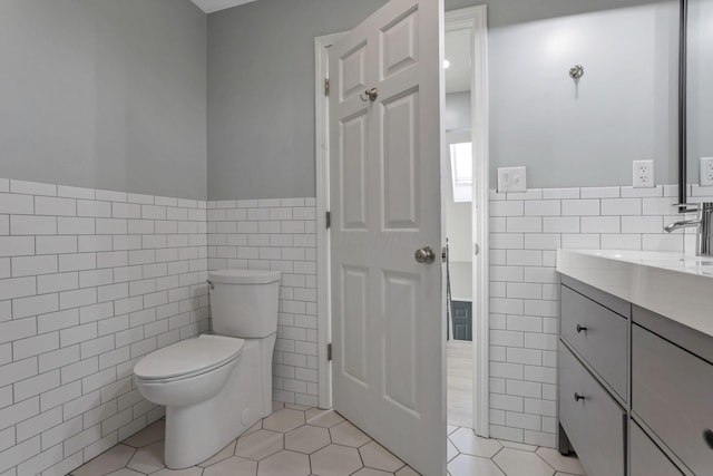 bathroom with tile walls, vanity, tile patterned floors, and toilet