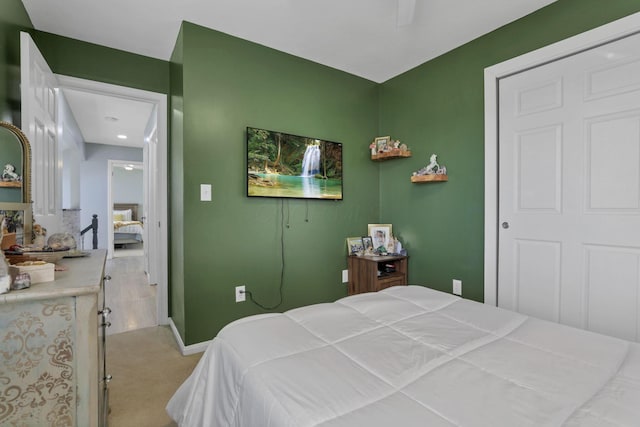 bedroom featuring light colored carpet, a closet, and ceiling fan