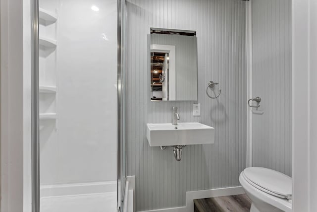 bathroom featuring sink, wood-type flooring, a shower with door, and toilet