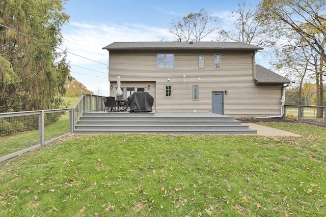 rear view of property with a wooden deck and a lawn