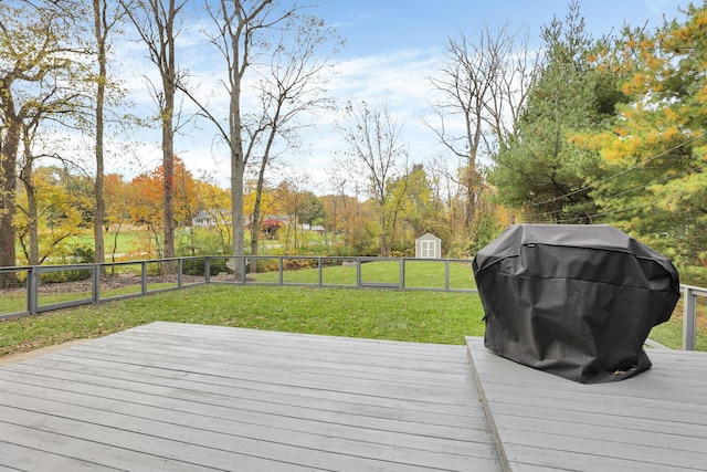 wooden deck with a storage shed, a grill, and a lawn