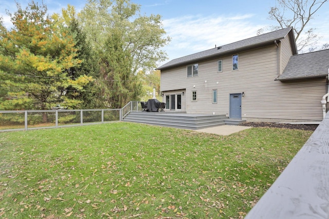 back of property featuring a wooden deck and a yard