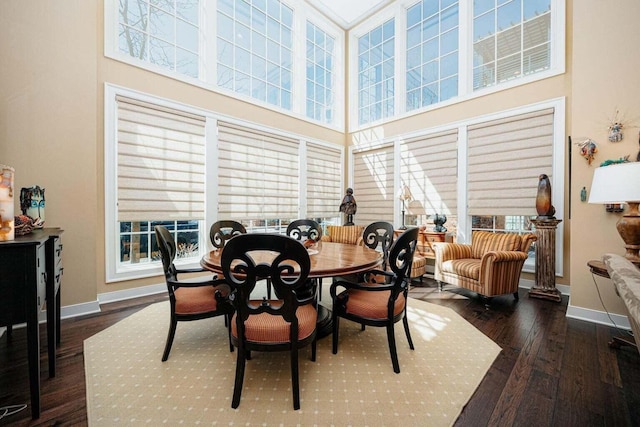 dining area featuring a towering ceiling, plenty of natural light, and dark wood-type flooring