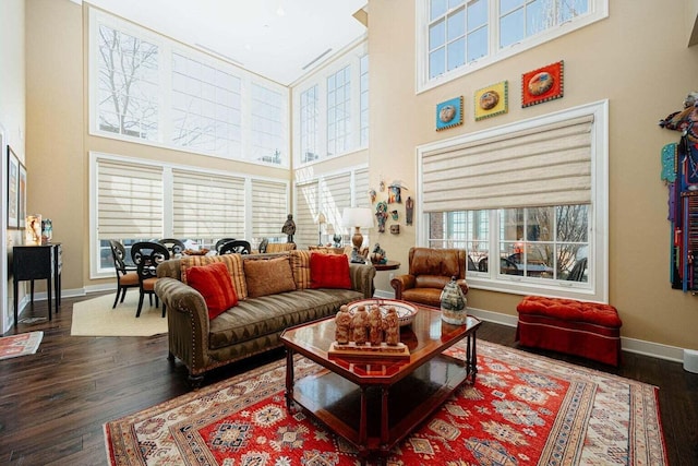 living room featuring a towering ceiling and dark wood-type flooring