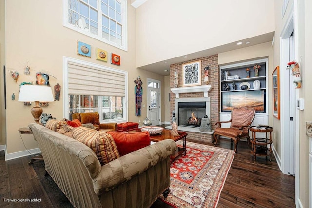 living room featuring a fireplace, a towering ceiling, dark wood-type flooring, and built in features