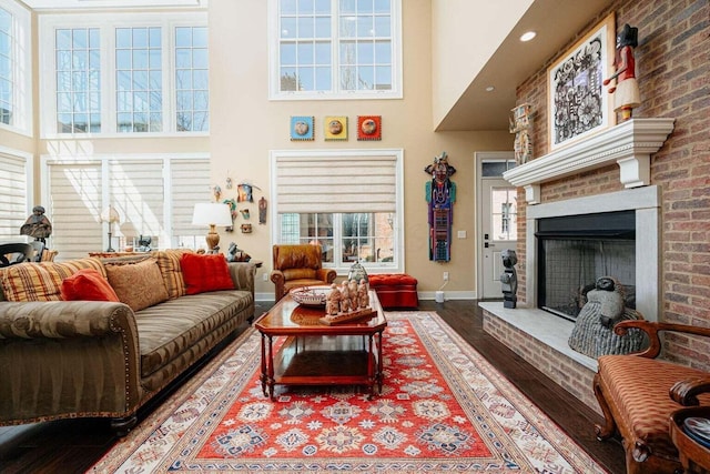 living room with a fireplace, hardwood / wood-style floors, a wealth of natural light, and a high ceiling