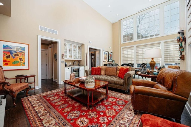 living room with bar, wine cooler, high vaulted ceiling, and dark wood-type flooring