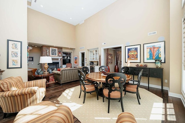 dining space with dark hardwood / wood-style flooring, a fireplace, and a high ceiling