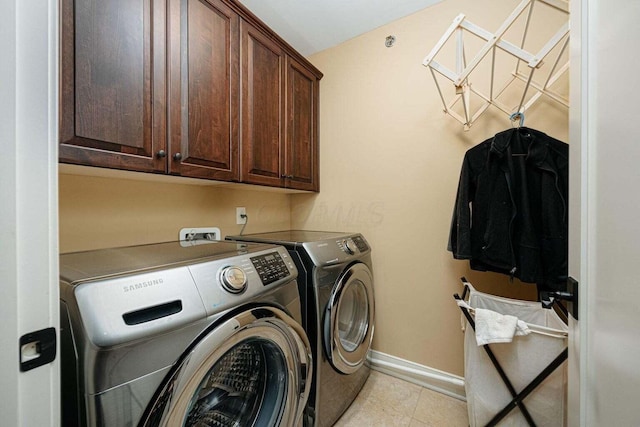 laundry room with washer and clothes dryer, light tile patterned flooring, and cabinets