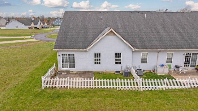 rear view of property featuring a lawn, central AC, and a patio