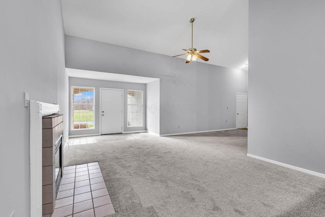 unfurnished living room with light carpet, a tile fireplace, high vaulted ceiling, and ceiling fan