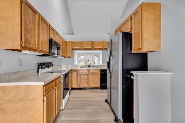 kitchen with black appliances, lofted ceiling, sink, and light hardwood / wood-style flooring