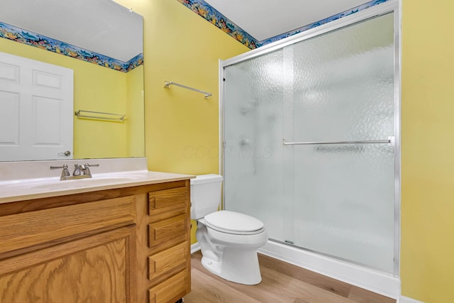 bathroom with hardwood / wood-style floors, vanity, toilet, and a shower with shower door