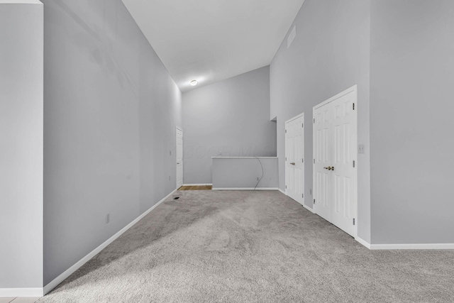 carpeted spare room with vaulted ceiling