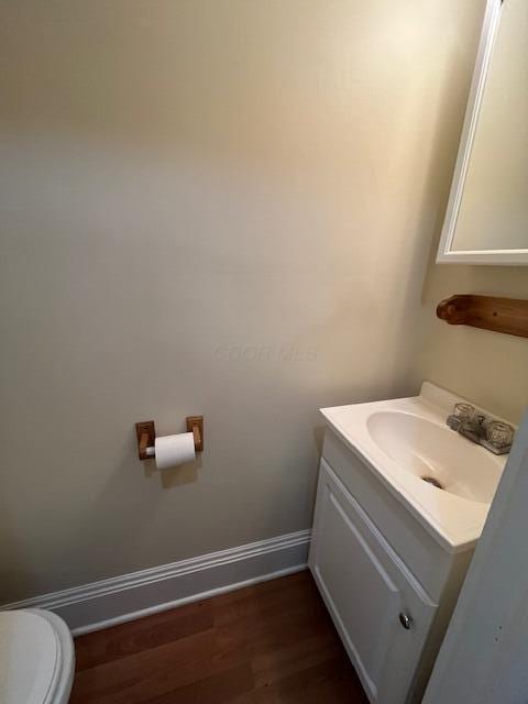 bathroom with toilet, vanity, and hardwood / wood-style flooring