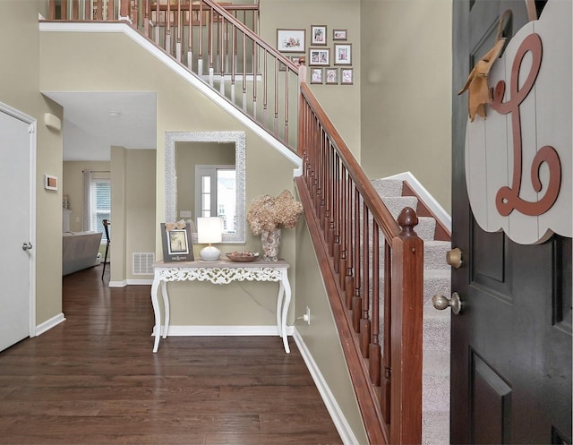 stairs with hardwood / wood-style floors and a high ceiling