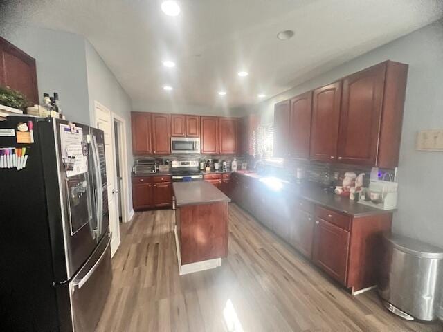 kitchen featuring a center island, wood-type flooring, backsplash, and appliances with stainless steel finishes