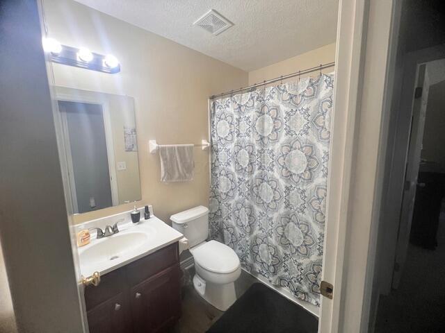 bathroom featuring a shower with curtain, vanity, a textured ceiling, and toilet