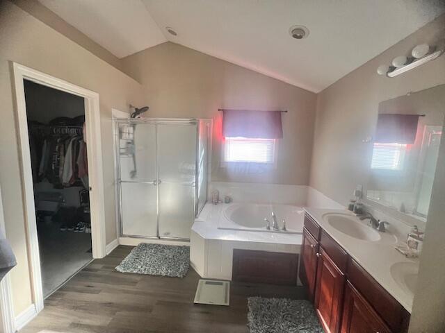 bathroom with vanity, independent shower and bath, vaulted ceiling, and wood-type flooring