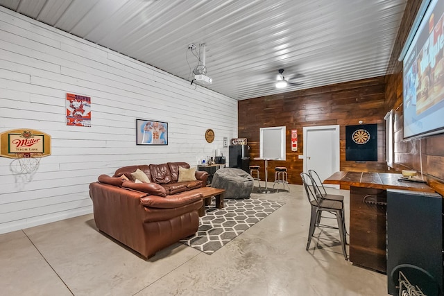 living room featuring ceiling fan and wooden walls