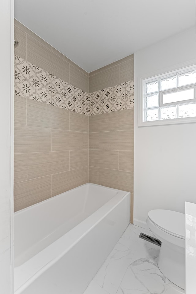 bathroom featuring tiled shower / bath combo and toilet