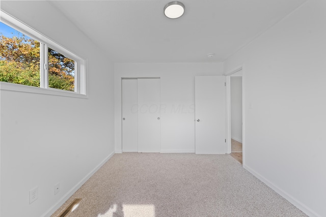 unfurnished bedroom featuring light carpet and a closet