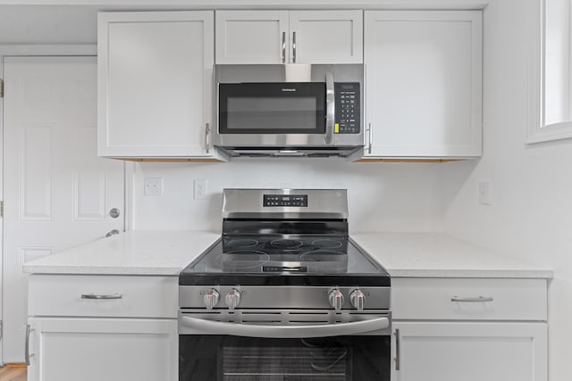 kitchen with white cabinets, light stone counters, and stainless steel appliances