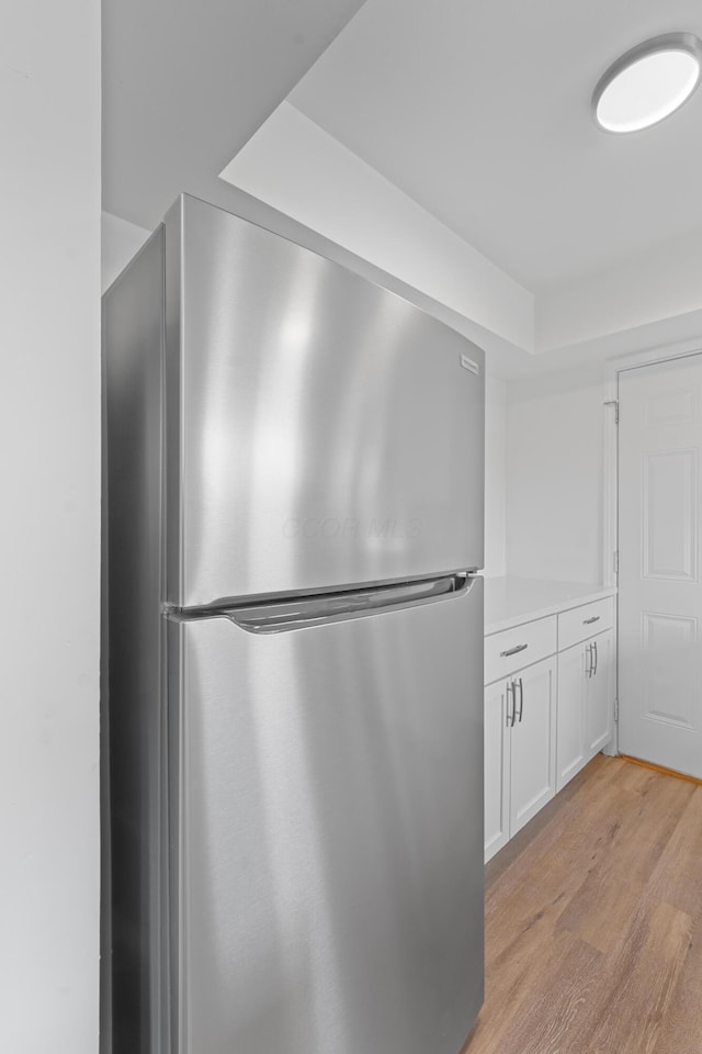 kitchen featuring stainless steel refrigerator, white cabinets, and light hardwood / wood-style floors