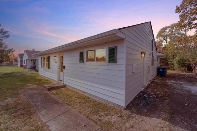 property exterior at dusk featuring a lawn