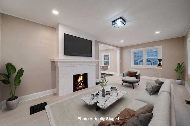 living room with light wood-type flooring and a brick fireplace