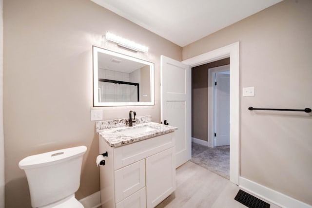 bathroom with walk in shower, hardwood / wood-style flooring, vanity, and toilet