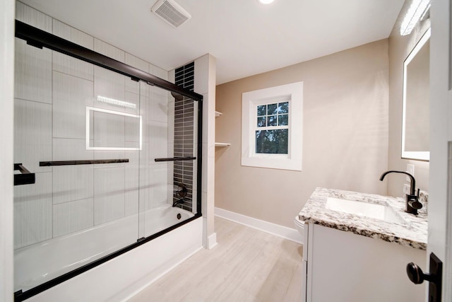 bathroom with combined bath / shower with glass door, vanity, and hardwood / wood-style flooring