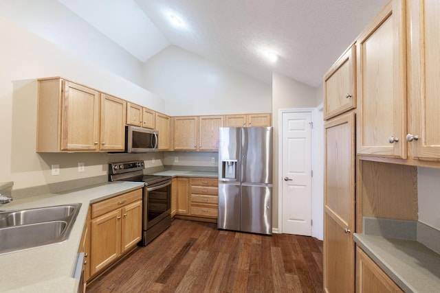 kitchen featuring appliances with stainless steel finishes, dark hardwood / wood-style floors, light brown cabinets, lofted ceiling, and sink