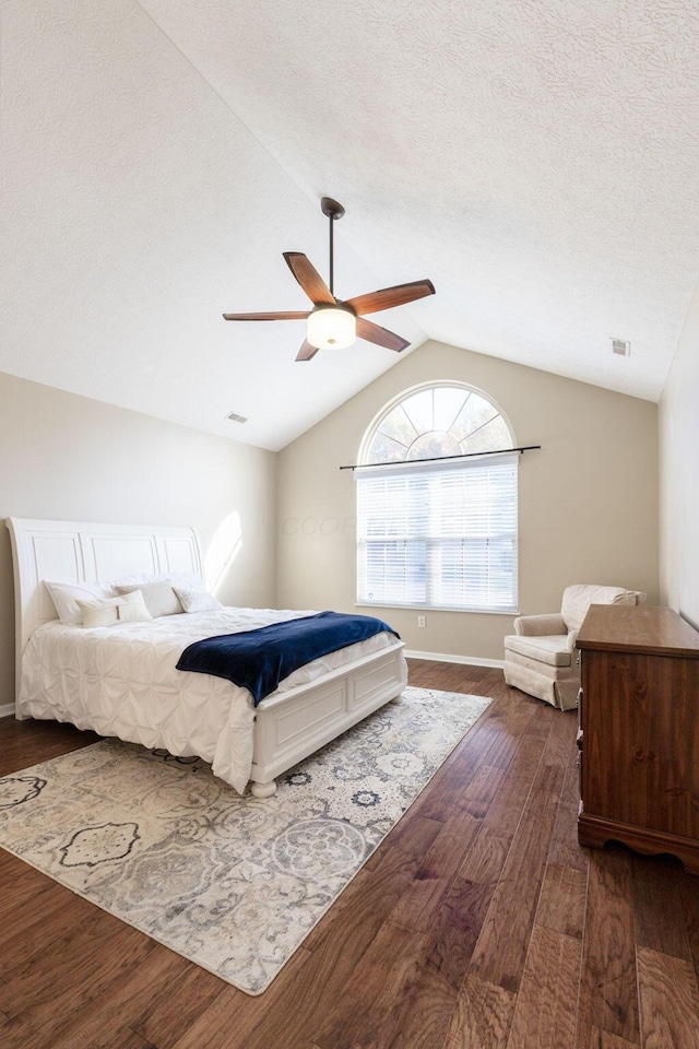 bedroom with ceiling fan, vaulted ceiling, dark hardwood / wood-style flooring, and a textured ceiling